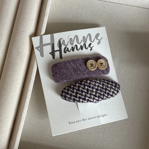 Détail de barrettes à cheveux en tweed violet avec boutons en bois et motif pied-de-poule