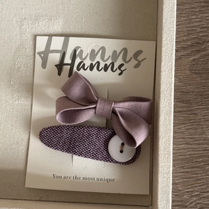 Détail des barrettes à nœud papillon en tissu violet et accessoire à bouton sur carte