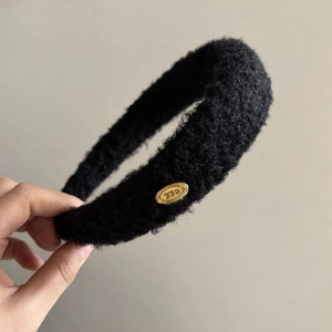 Minimalist black plush sponge headband with gold metal tag for high skull top hair look