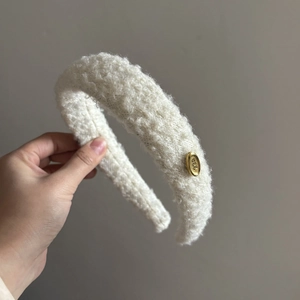 Plush white lamb wool headband with a gold metal EGG logo for high crown hair styling