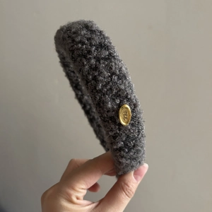 Detailed side view of thick gray fleece headband with gold metal egg logo plate