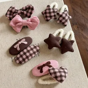 Detail of pink plaid bow hair clips and plush star hairpins on a vintage book surface