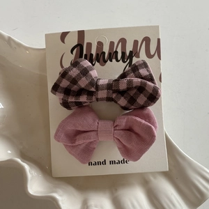 Detailed view of pink plaid and solid fabric bow hair clips on a handmade card display