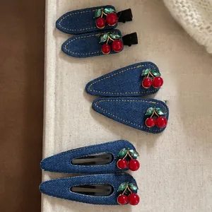 Vue détaillée de pinces à cheveux en denim bleu foncé avec cerises rouges et strass brillants