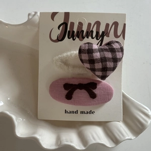 Pink plaid heart and bow hair clips set displayed on white shell ceramic plate