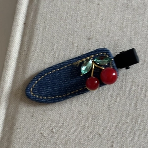 Détail de la pince à cheveux en denim avec cerises en cristal rouge et coutures jaunes