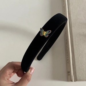 Detail of a vintage black velvet headband with a blue and gold butterfly charm
