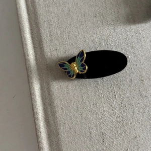 Macro detail of blue velvet butterfly hair clip with gold metal edges and enamel details