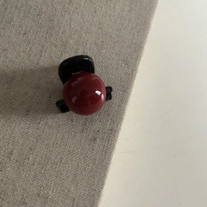 Pince à cheveux élégante avec perles rouge foncé et sphères brillantes sur fond de tissu gris