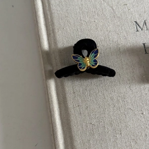 Vintage velvet butterfly hair clip with blue and gold gradients on a textured book