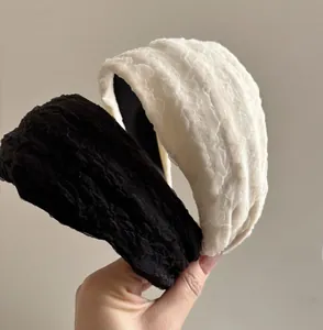 Close-up of wide chiffon lace headband showing textured fabric detail in black and white