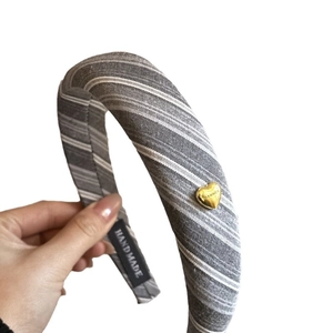 Padded headband with grey striped fabric and a gold heart metal buckle detail