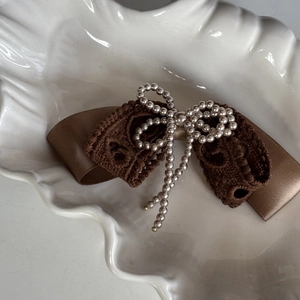 Vintage brown lace satin bow hair clip with pearl butterfly detail on white plate