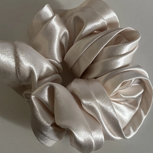 Elegant champagne satin scrunchie with ruffled pleats on a clean white background