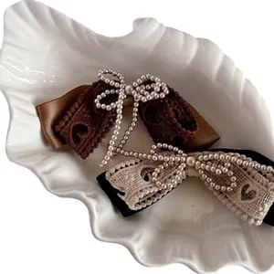 Vintage lace bow hair clips with pearls on shell dish, retro hair accessories for women