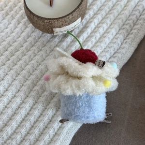 Cute plush cupcake hair clip with red cherry on soft knitted background, top view
