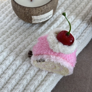 Close-up of pink plush cake hair clip with soft cream detail and cherry on top