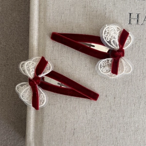 Pinza de terciopelo rojo con lazo de encaje blanco sobre un libro de estilo retro