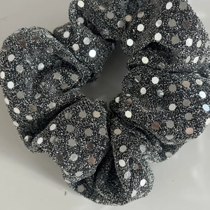 Detailed view of large silver sequin hair scrunchie with sparkling fabric texture