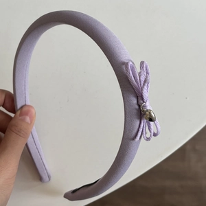 Vue détaillée d'un serre-tête en tissu violet avec un nœud et un pendentif cœur argenté