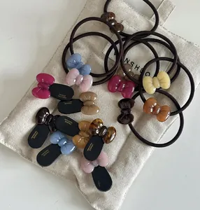 Flat lay of colorful resin bow hair ties with high elasticity bands on a beige linen bag
