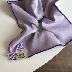Détail d'un chouchou en dentelle violette avec nœud et breloque cœur en métal