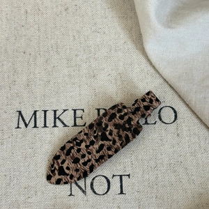 Close-up of leopard print hair clip showing detailed pattern on natural canvas background