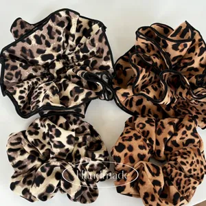 Detailed set of 4 leopard print scrunchies in cream and brown patterns on white background