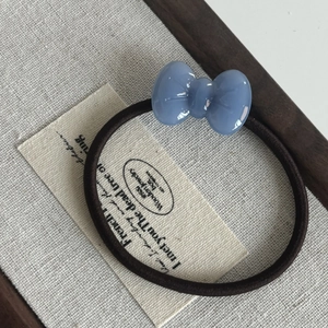 Macro detail of a light blue acetate bow hair tie with a durable elastic woven cord