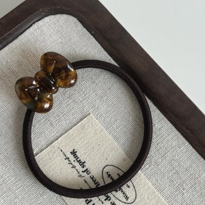 Detail of amber tortoiseshell acetate bow hair tie on rustic linen display card