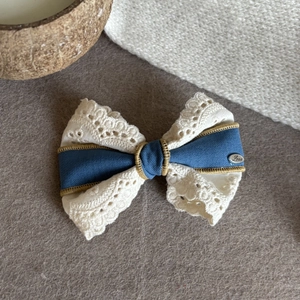 Détail de la pince à cheveux nœud en dentelle et denim avec pièce métallique gravée Love