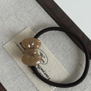Macro shot of khaki acetate bow decoration on a durable brown elastic hair tie