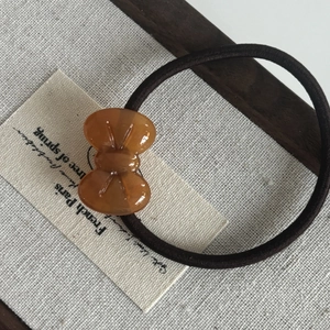 Sweet amber bow acetate hair tie with high elasticity rubber band on linen background