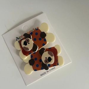 Detail of two brown puppy hair clips with blue dots on a white display card pack