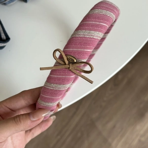 Close-up of pink and white striped padded headband with brown bow and gold Love charm