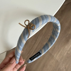Close-up of blue striped headband with suede bow and love metal tag detail