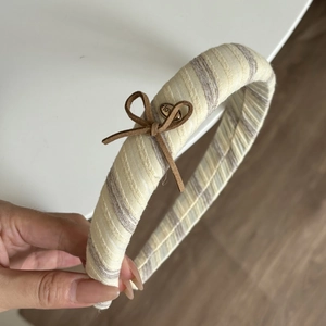 Detail of striped fabric headband with sponge padding and a heart-shaped metal charm