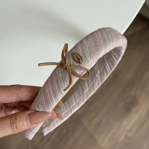 Striped pink fabric headband with a brown bow and engraved metal love plate detail