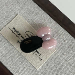 Pink acetate bow hair clip with France Handmade lettering on a textured linen fabric background