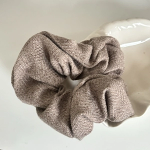 Oatmeal linen hair scrunchie with herringbone texture on a white shell plate