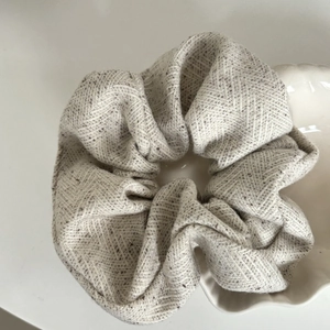 Detailed view of herringbone texture on beige cotton linen scrunchie in a ceramic dish