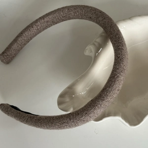 Detailed view of oatmeal brown thick wool hairband with non-slip black lining on shell plate