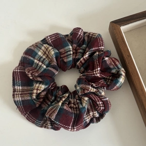 Macro detail of red and green plaid fabric scrunchie with classic British tartan pattern