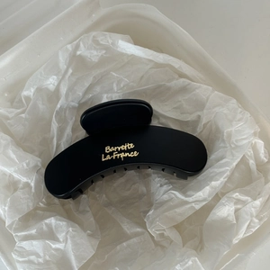 Close-up of matte black hair claw clip featuring golden Barrette La France lettering