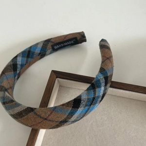 Detail of tartan plaid headband with a black handmade label on wooden tray