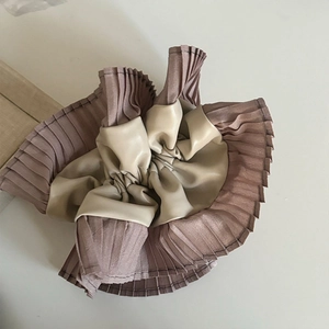 Detailed view of the layered pleats and two-tone leather lace texture on the hair scrunchie