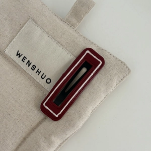 Minimalist canvas bag detail featuring woven Wenshuo logo label and textured red accent