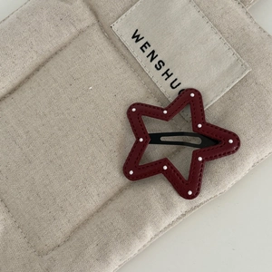 Close-up of star-shaped dark red leather hair clip with white dots and BB clip detail