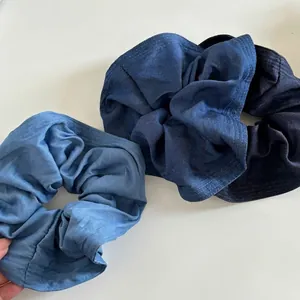 Three-piece denim scrunchies set in light to dark blue shades with a soft fabric texture