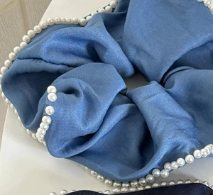 Detail of blue denim style scrunchie featuring elegant white faux pearls and silky texture